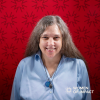 Dr. McKay-Cody, wearing a light blue blouse in front of a red background