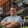 Octreyvian Killian standing outside, arms crossed, in front of a UA bldg