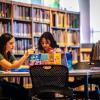 adult and child sitting at a table in a library