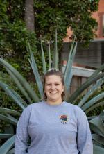 Lesley A Lafferty headshot, wearing a gray long sleeve shirt, standing in front of an agave plant