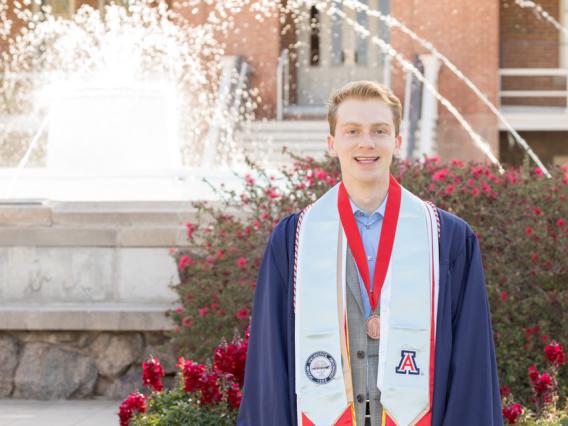 Brennen Feder graduation photo in front of old main fountain