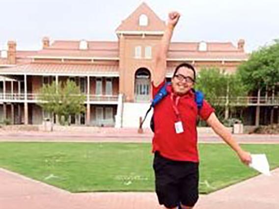 Student jumping up with a fist pump in front of old main
