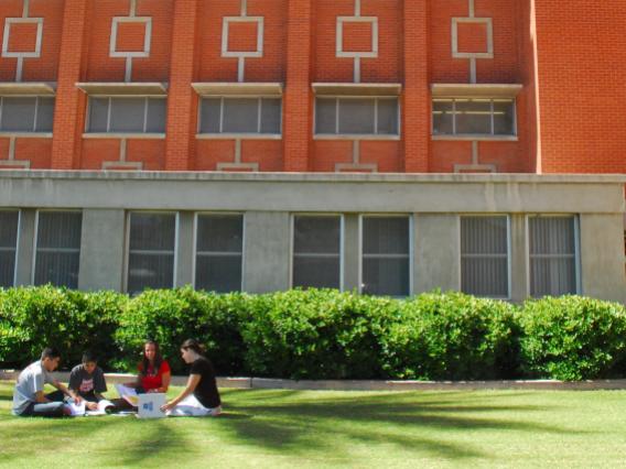 students sitting on green lawn in front of the college of education building