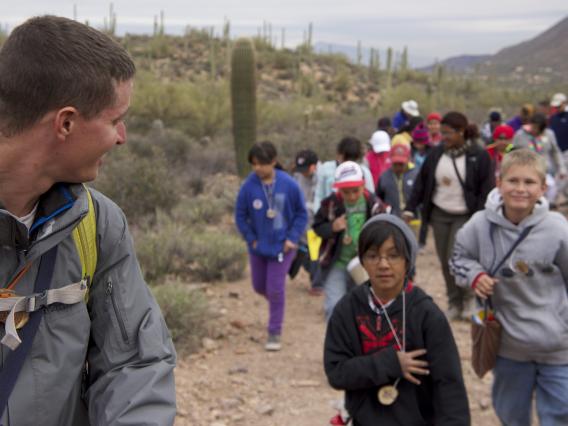 several children following a guide on a desert trail