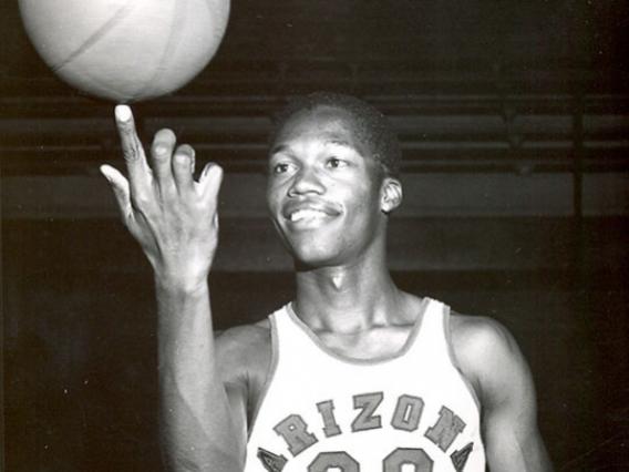 Ernie McCray in uniform spinning a basketball on his finger