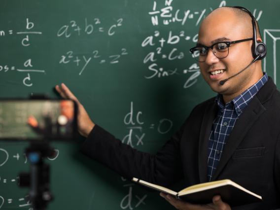african american male with a headset at a chalkboard with headset on being filmed