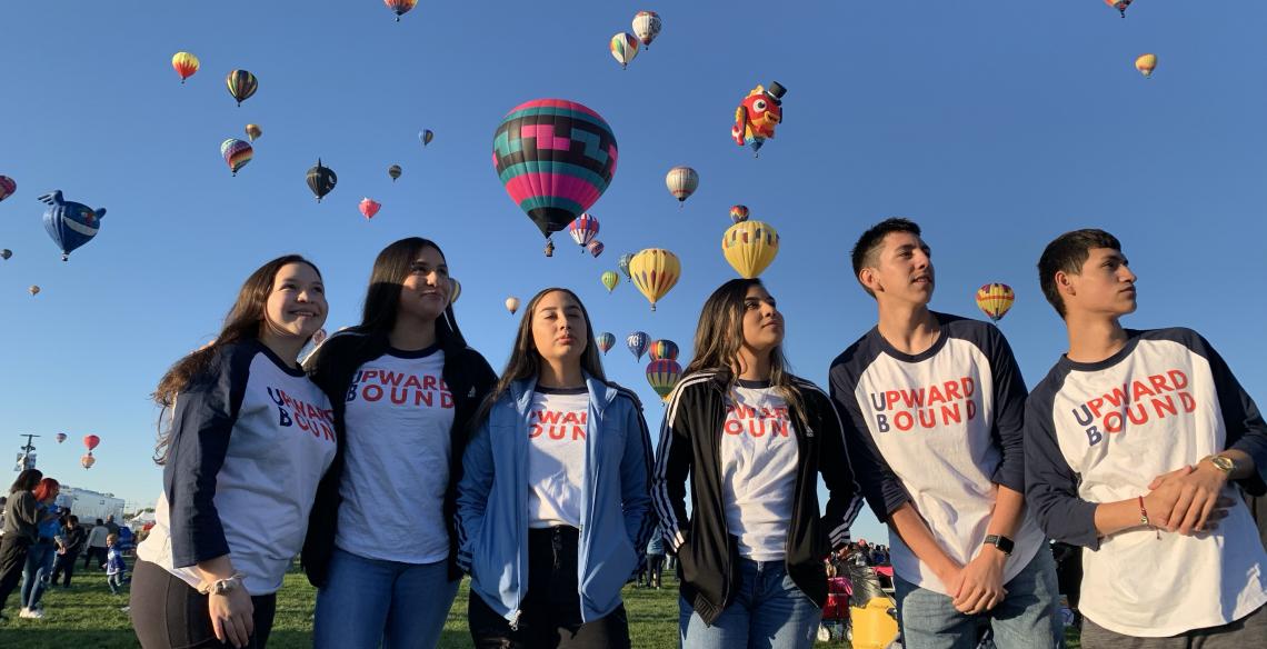 students looking up at hot air balloons