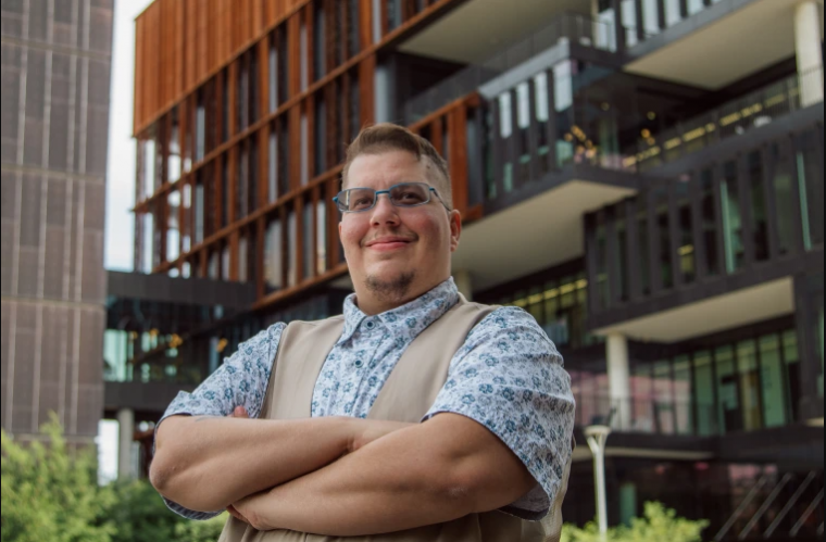 Octreyvian Killian standing outside, arms crossed, in front of a UA bldg