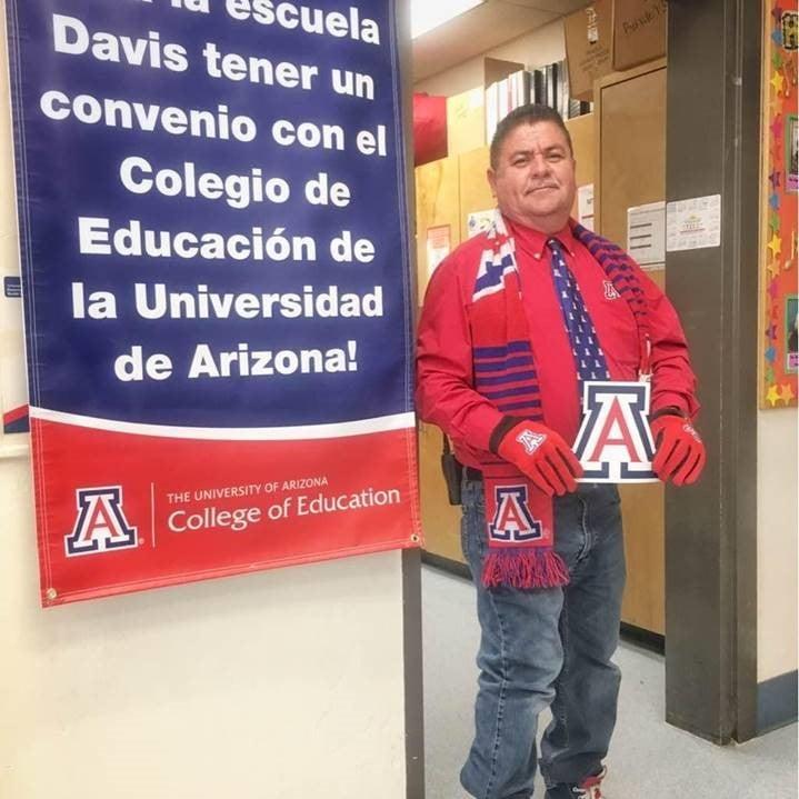 Jose Olivas in UA gear standing next to spanish language banner