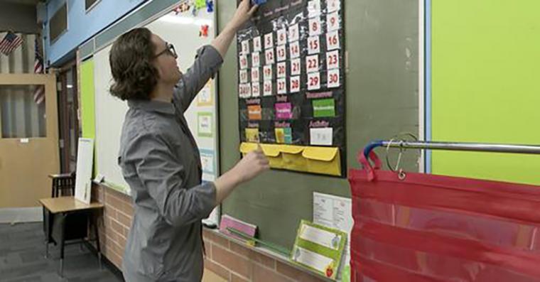 mark anthony ferguson in the classroom tending to a hanging calendar