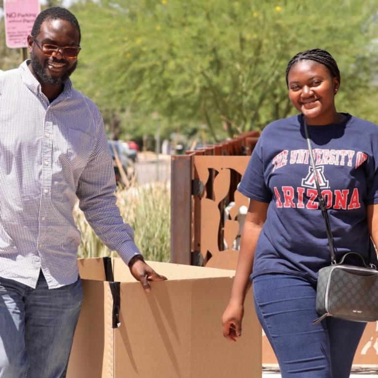 african american dad and daughter walking on campus under a sunny sky