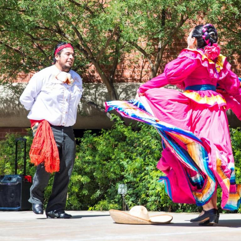 one male and one female folklorico dancer on stage in colorful garments