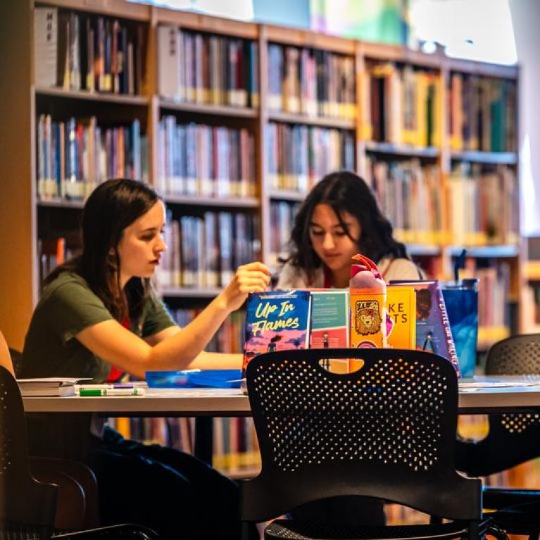 adult and child sitting at a table in a library