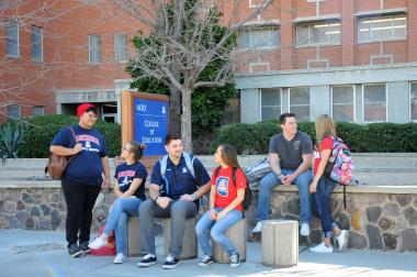 group of students sitting in front of college of education buidling